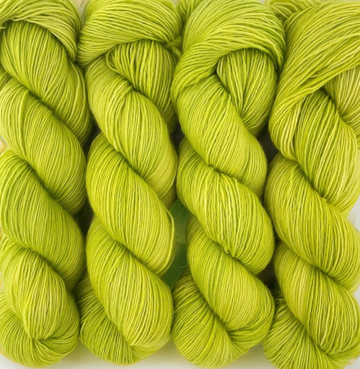 Four skeins of extrafine superwash sock weight merino wool, hand dyed lime green.