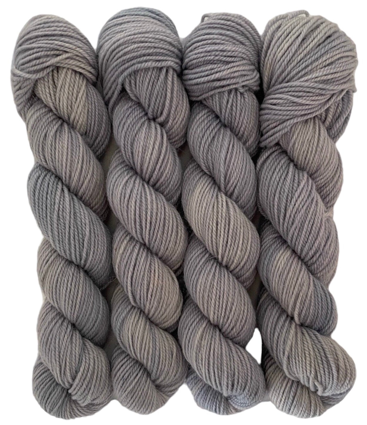 Four skeins of grey merino and blue faced Leicester non-superwash yarn on a white background. Hand dyed. DK