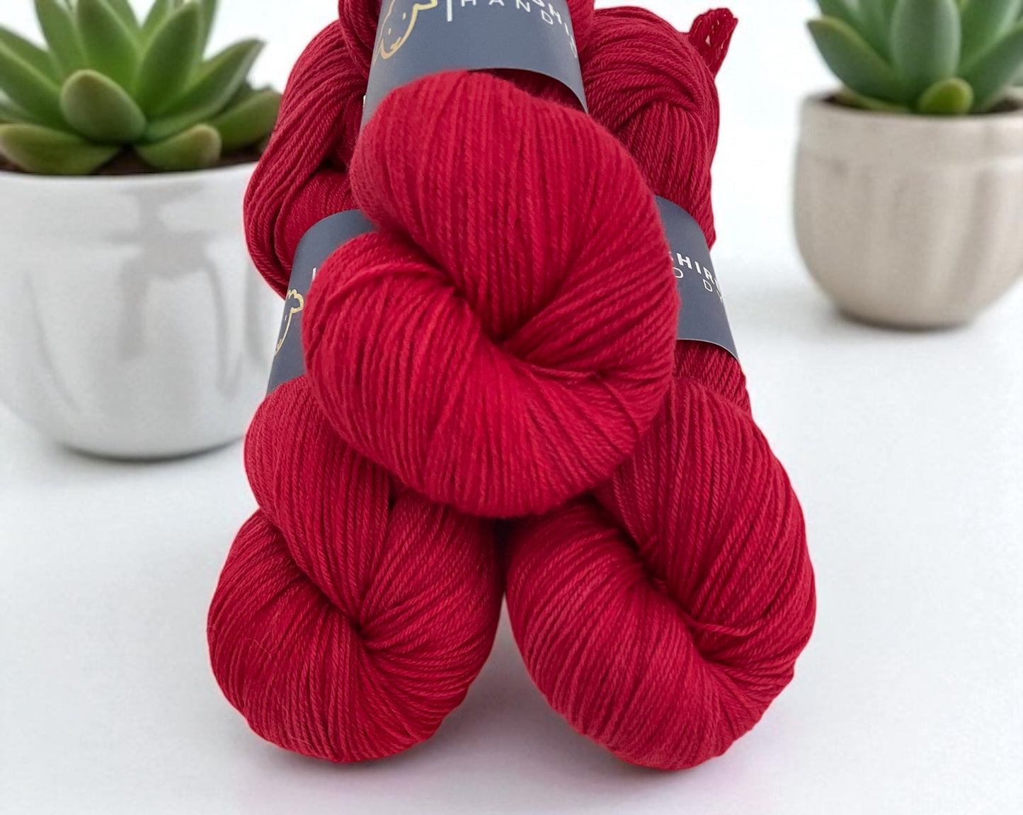 Three skeins of non superwash fingering weight sustainable merino wool, hand dyed red.