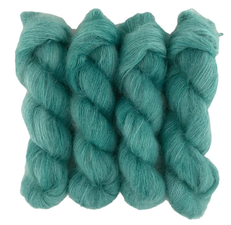 Four green hand dyed skeins of lace weight mohair and silk yarn on a white background.