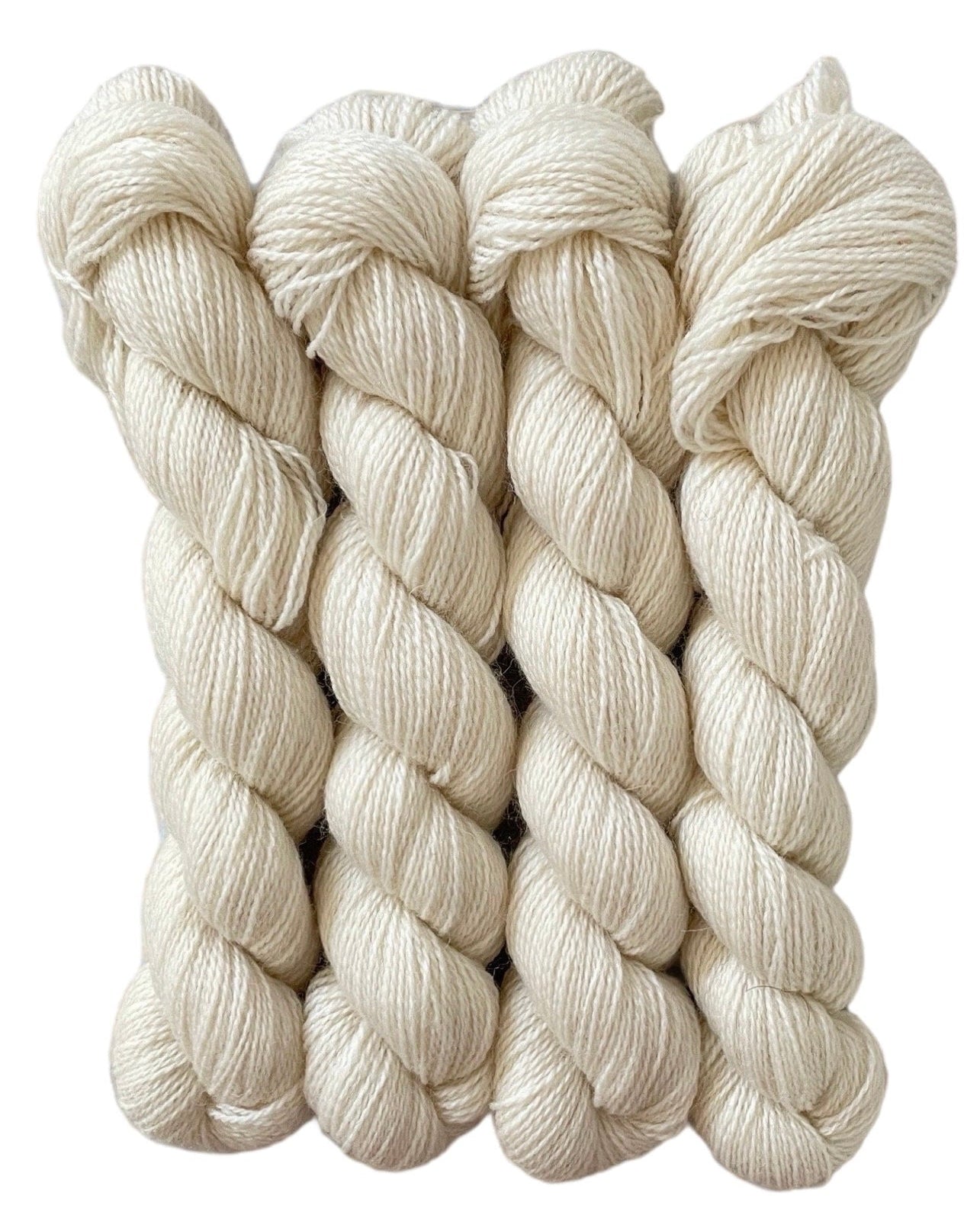 Four skeins of undyed beige and cream non superwash merino and bluefaced leicester sock weight yarn.