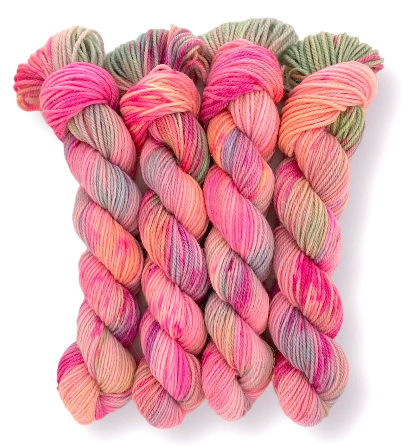 Four skeins of DK non superwash hand-dyed yarn in assorted colors, featuring a blend of Merino and Bluefaced Leicester fibers.