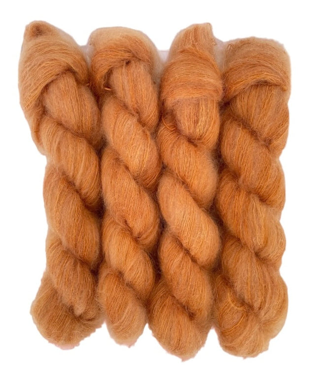 Four orange hand dyed skeins of lace weight mohair and silk yarn on a white background.
