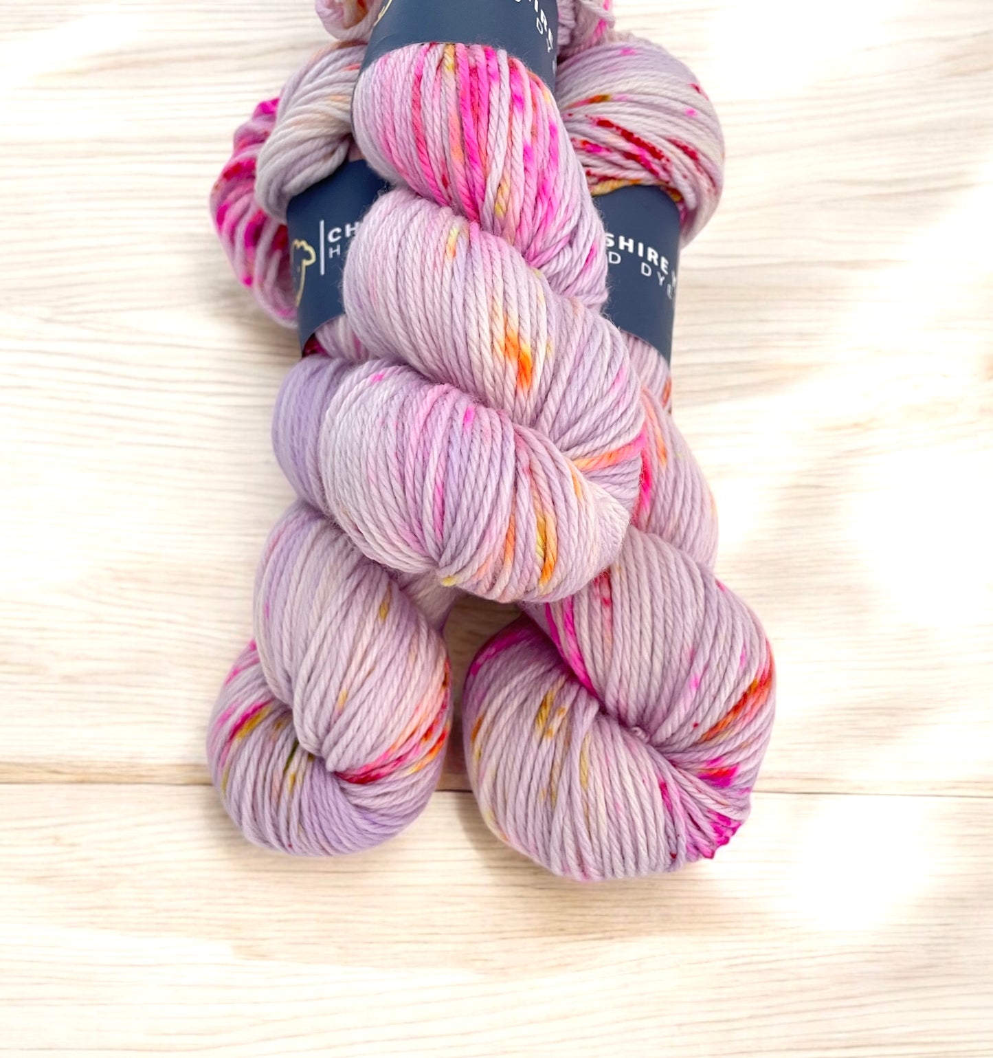 Close up of skeins of DK superwash merino and nylon yarn, hand dyed in shades of pink and lilac.