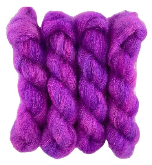 Four pink purple hand dyed skeins of lace weight mohair and silk yarn on a white background.