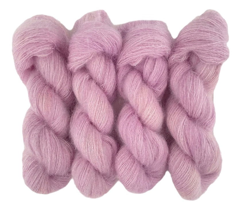Four pale pink hand dyed skeins of lace weight mohair and silk yarn on a white background.