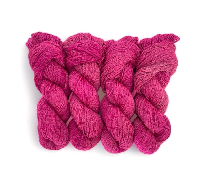 A skein of hand-dyed, semi-solid peony pink wool blend yarn.