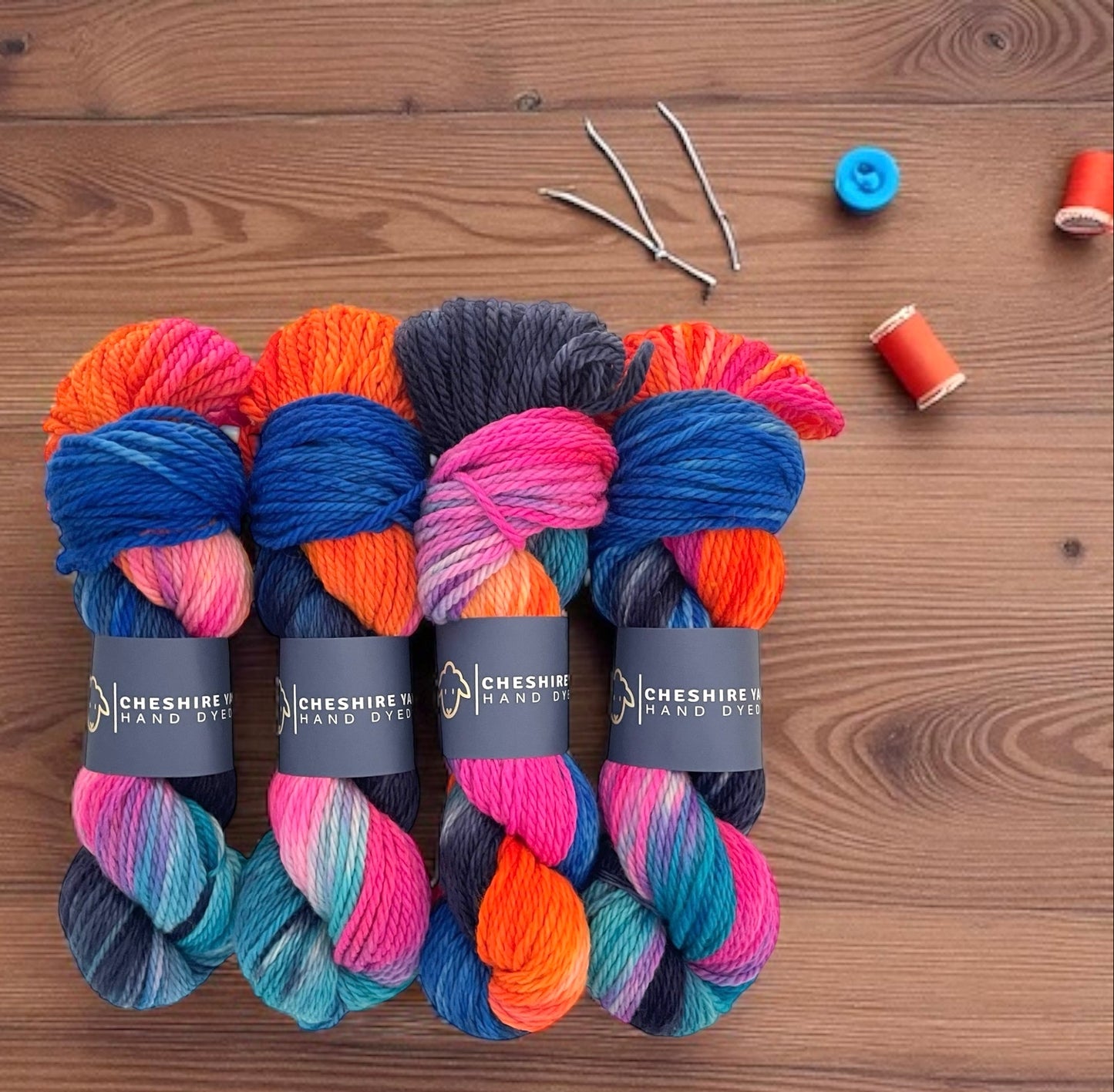 Four skeins of non superwash chunky weight merino wool, hand dyed in bright colours including blue, orange and pink.