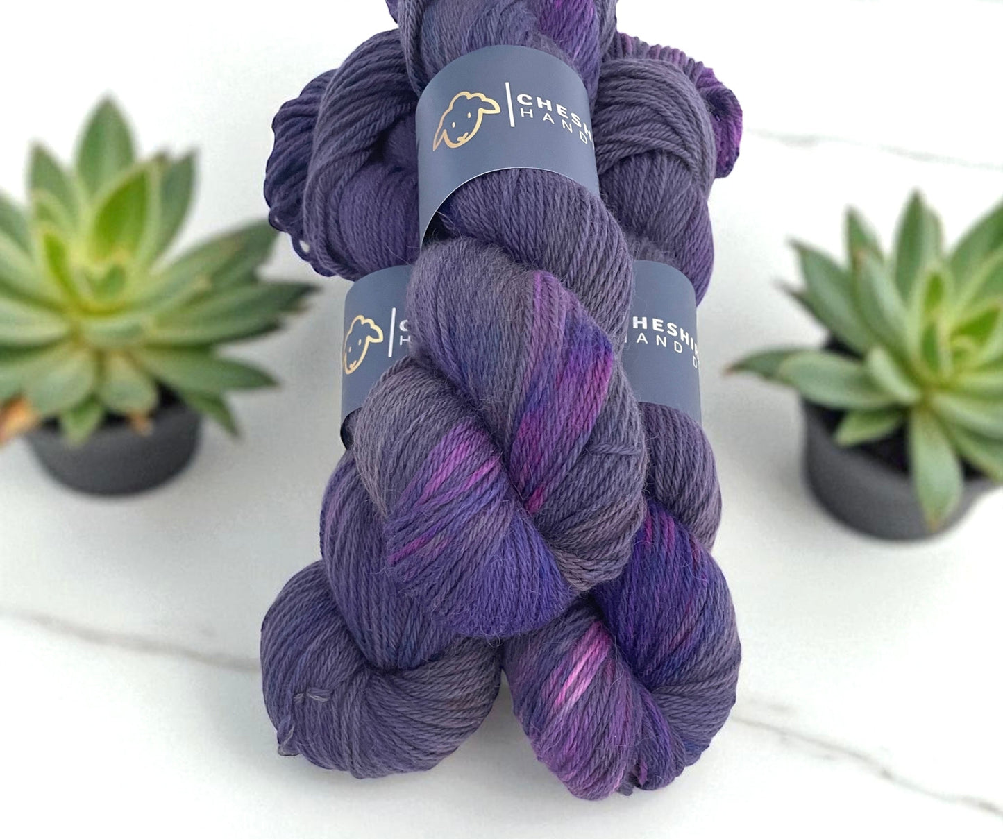 Three skeins of DK non superwash merino and alpaca yarn, hand dyed in shades of purple.