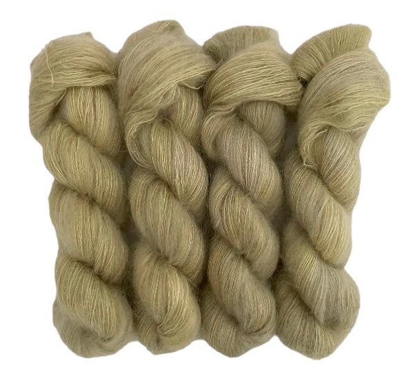 Four camel beige hand dyed skeins of lace weight mohair and silk yarn on a white background.
