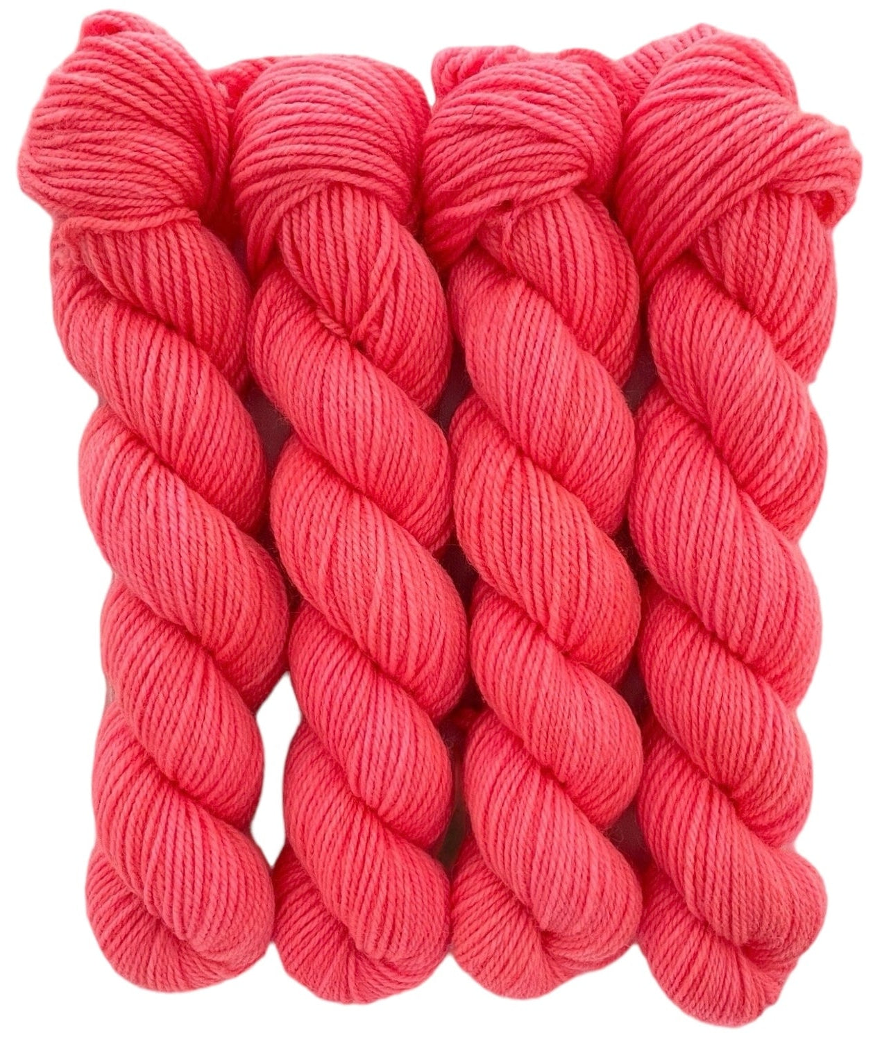 Four skeins of bright pink merino and blue faced Leicester non-superwash yarn on a white background. Hand dyed. DK
