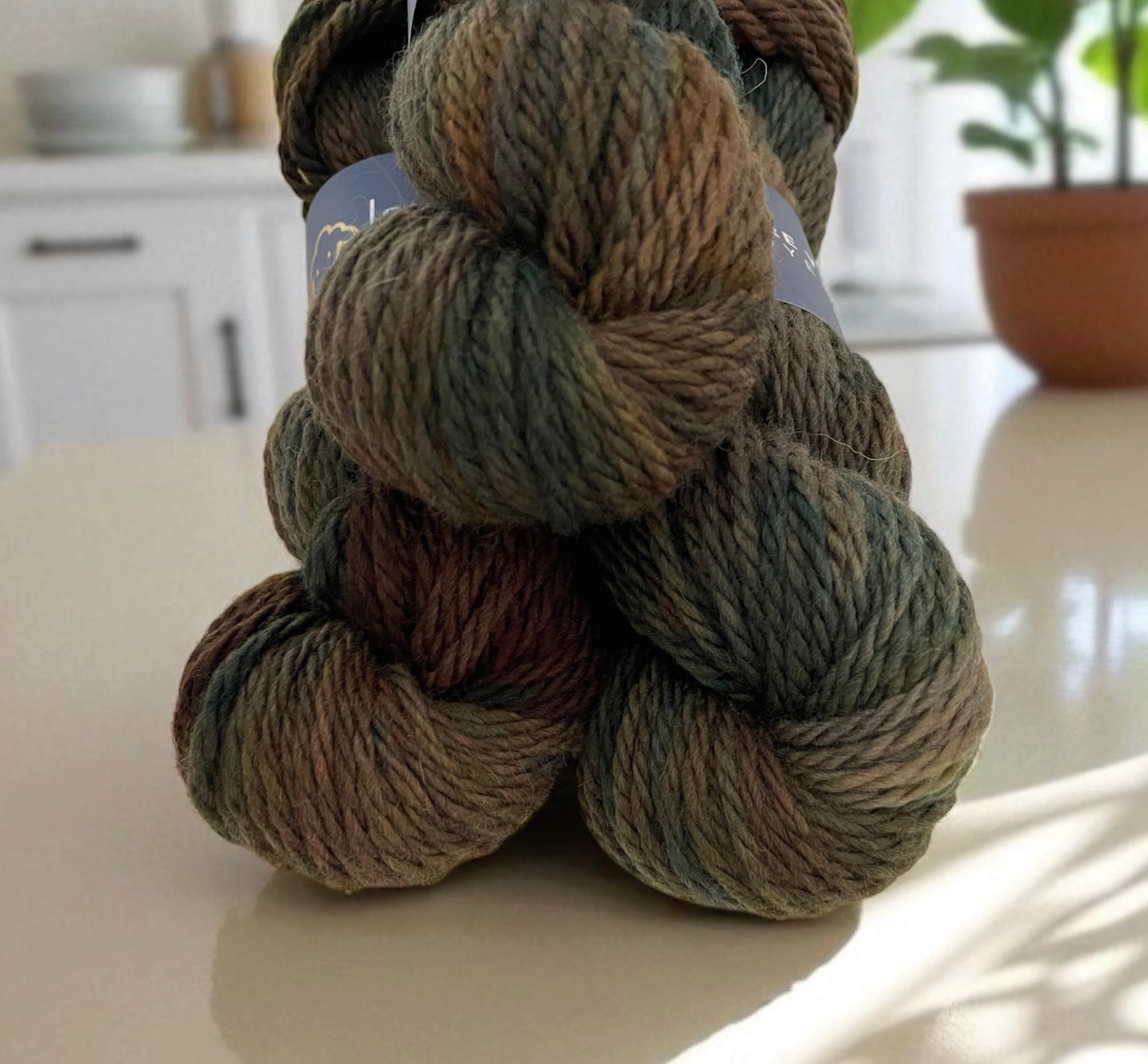 Close up of skeins of non superwash chunky weight merino wool, hand dyed in earthy brown, green and black.