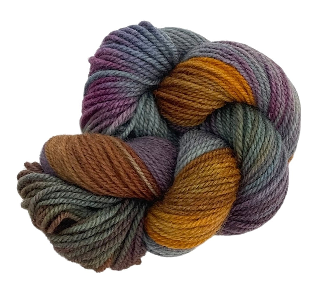Skein of multicolored hand dyed non superwash DK merino and bluefaced leicester yarn on a white background.