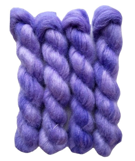 Four purple hand dyed skeins of lace weight mohair and silk yarn on a white background.