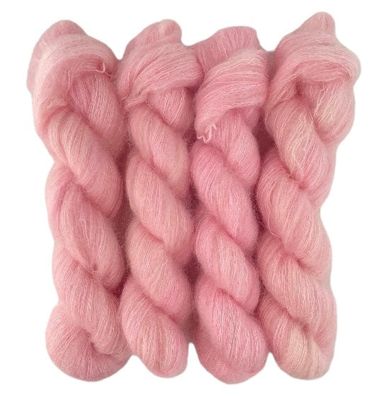 Four pale pink hand dyed skeins of lace weight mohair and silk yarn on a white background.