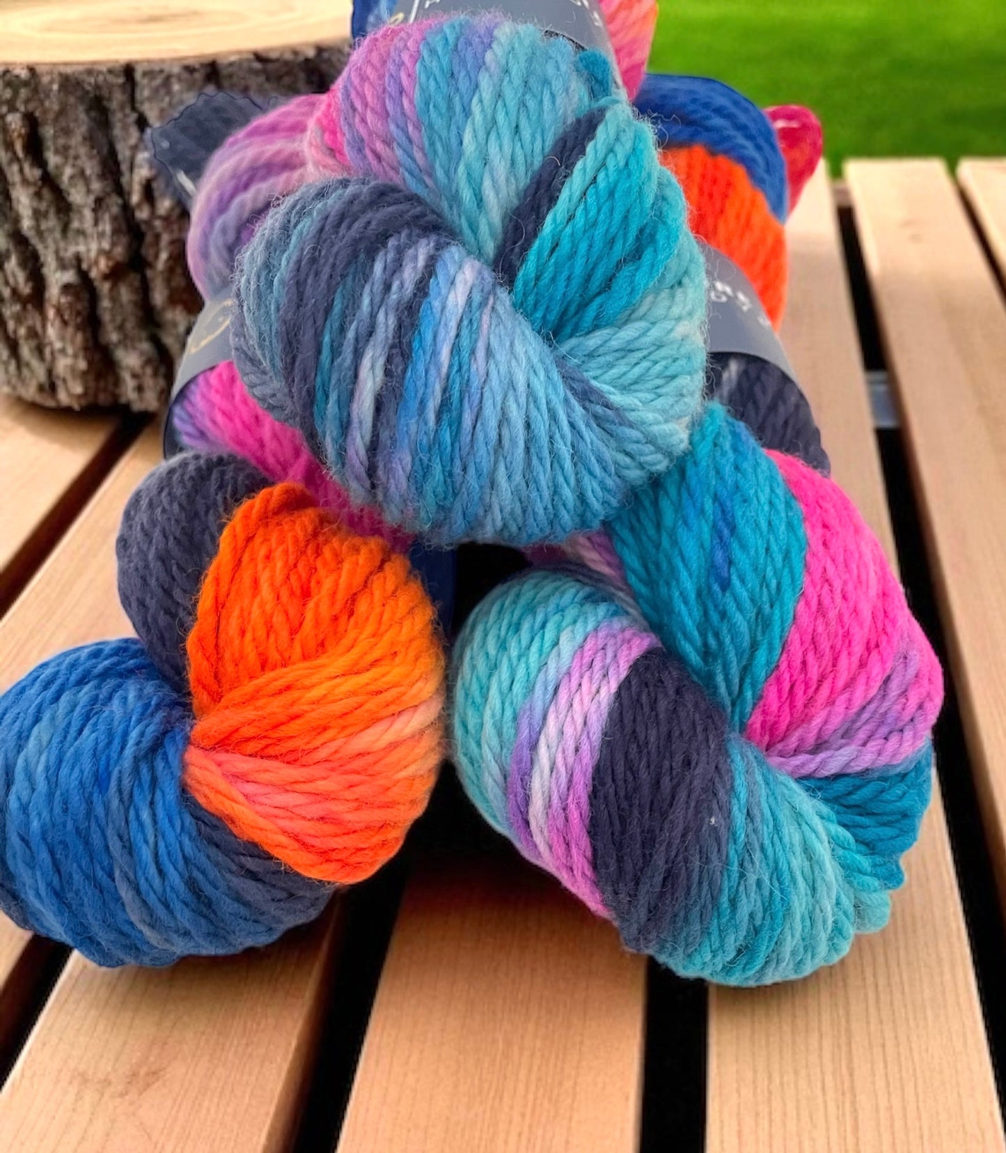 Close up of skeins of non superwash chunky weight merino wool, hand dyed in bright colours including blue, orange and pink.