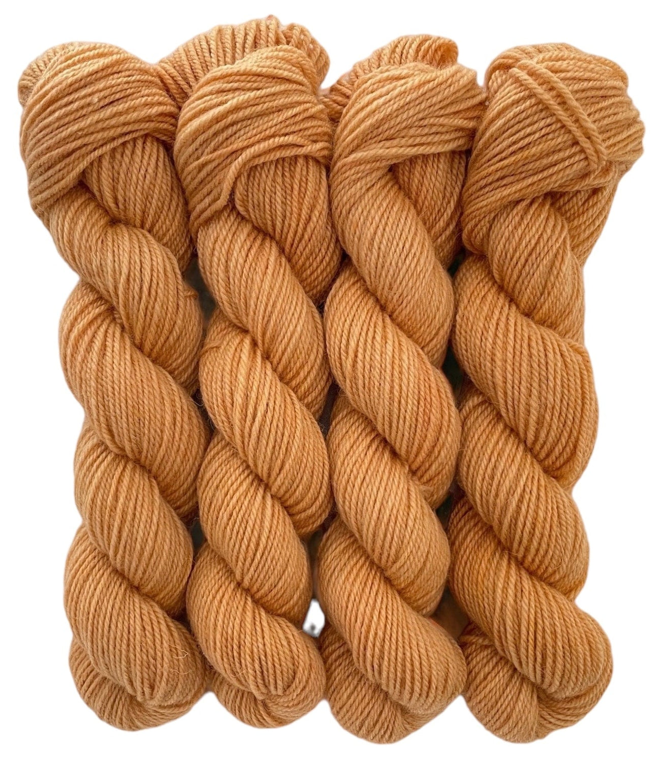 Four skeins of pale brown orange merino and blue faced Leicester non-superwash yarn on a white background. Hand dyed. DK
