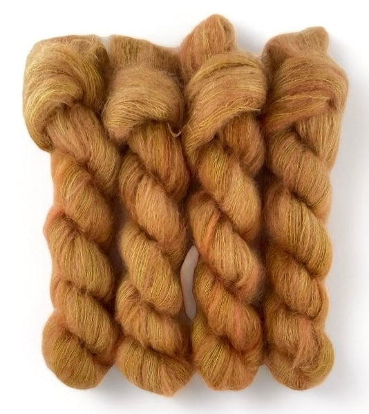 Four ginger brown hand dyed skeins of lace weight mohair and silk yarn on a white background.