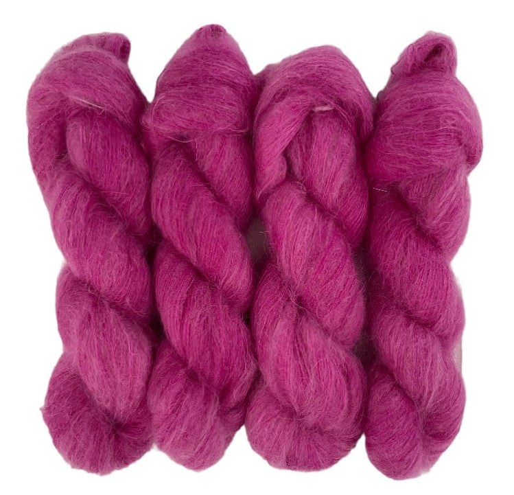 Four plum purple hand dyed skeins of lace weight mohair and silk yarn on a white background.