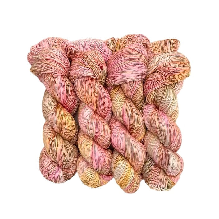 A skein of hand-dyed yarn in shades of pink, yellow, and beige.