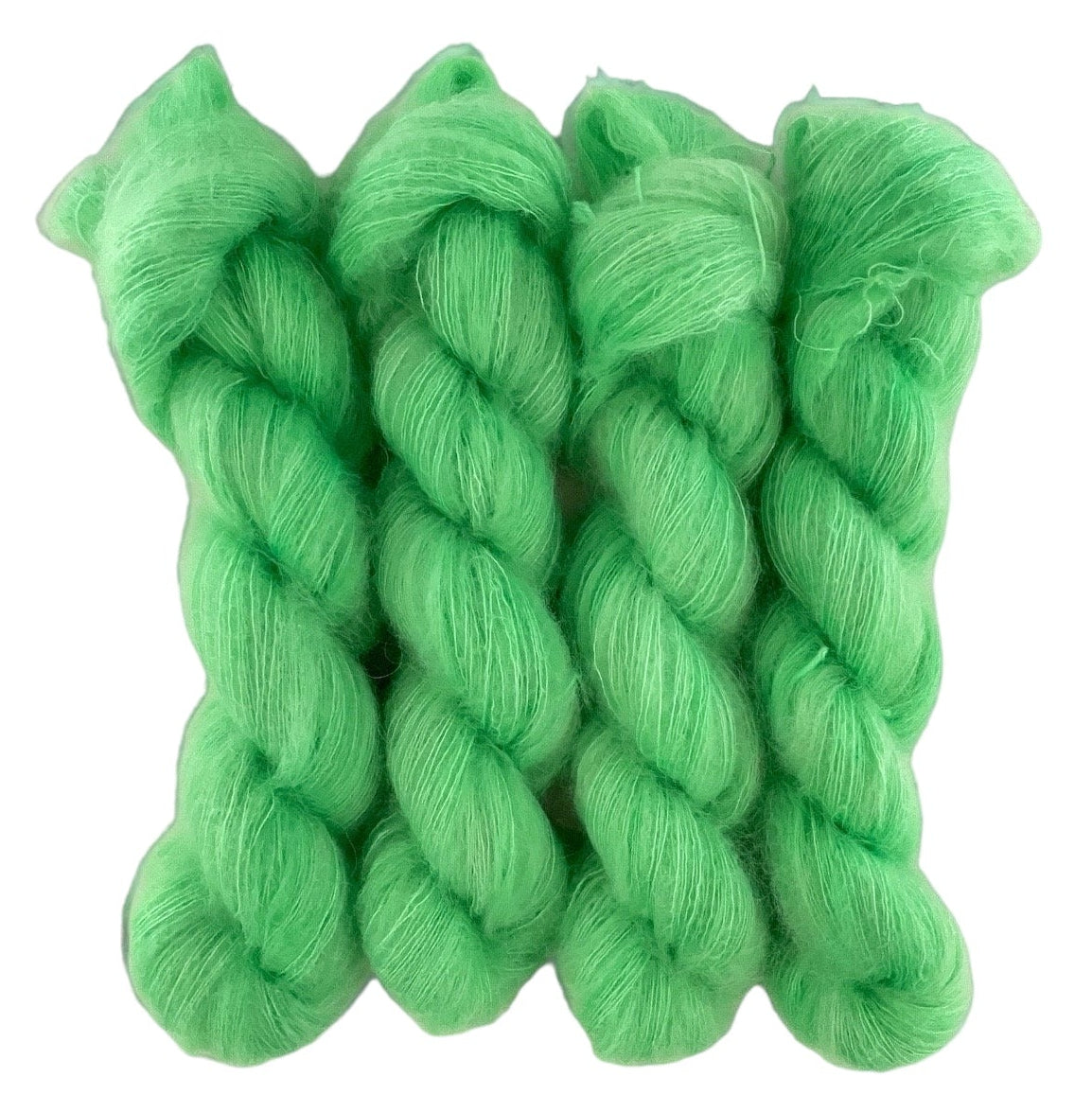 Four bright green hand dyed skeins of lace weight mohair and silk yarn on a white background.