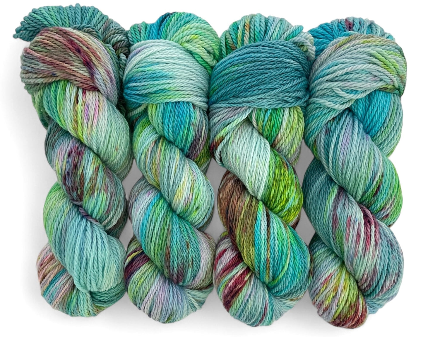 Four skeins of hand-dyed, multicolored aran weight non superwash merino yarn with a mix of blues, greens, yellows and browns.
