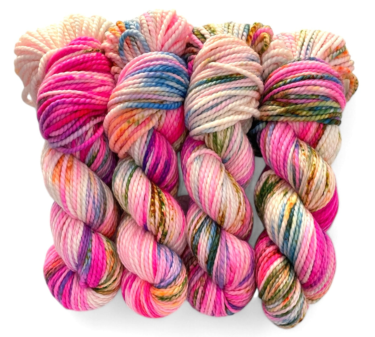 Four skeins of chunky weight superwash merino yarn, hand dyed in various colours including pink, blue, green and brown.