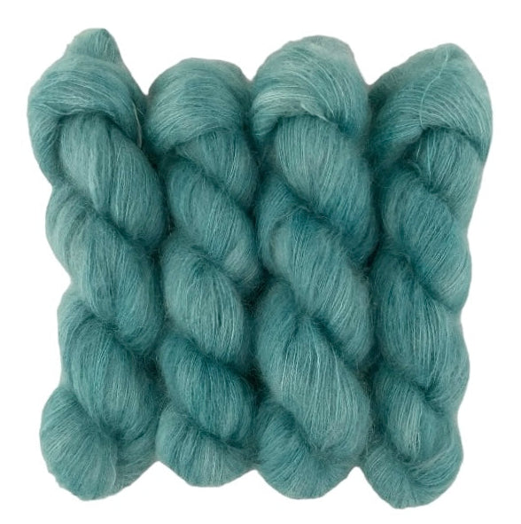 Four blue green hand dyed skeins of lace weight mohair and silk yarn on a white background.