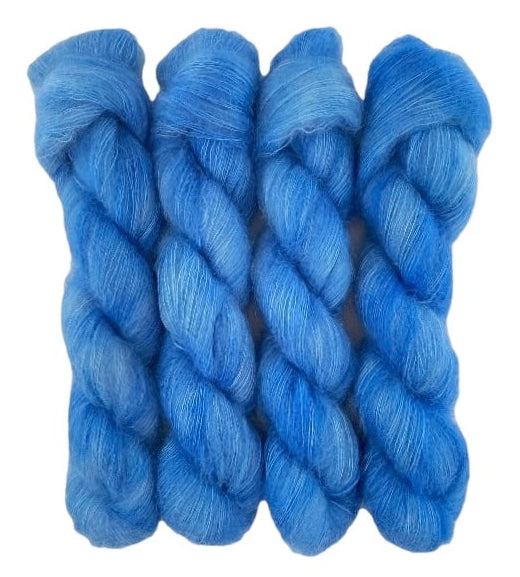 Four blue hand dyed skeins of lace weight mohair and silk yarn on a white background.