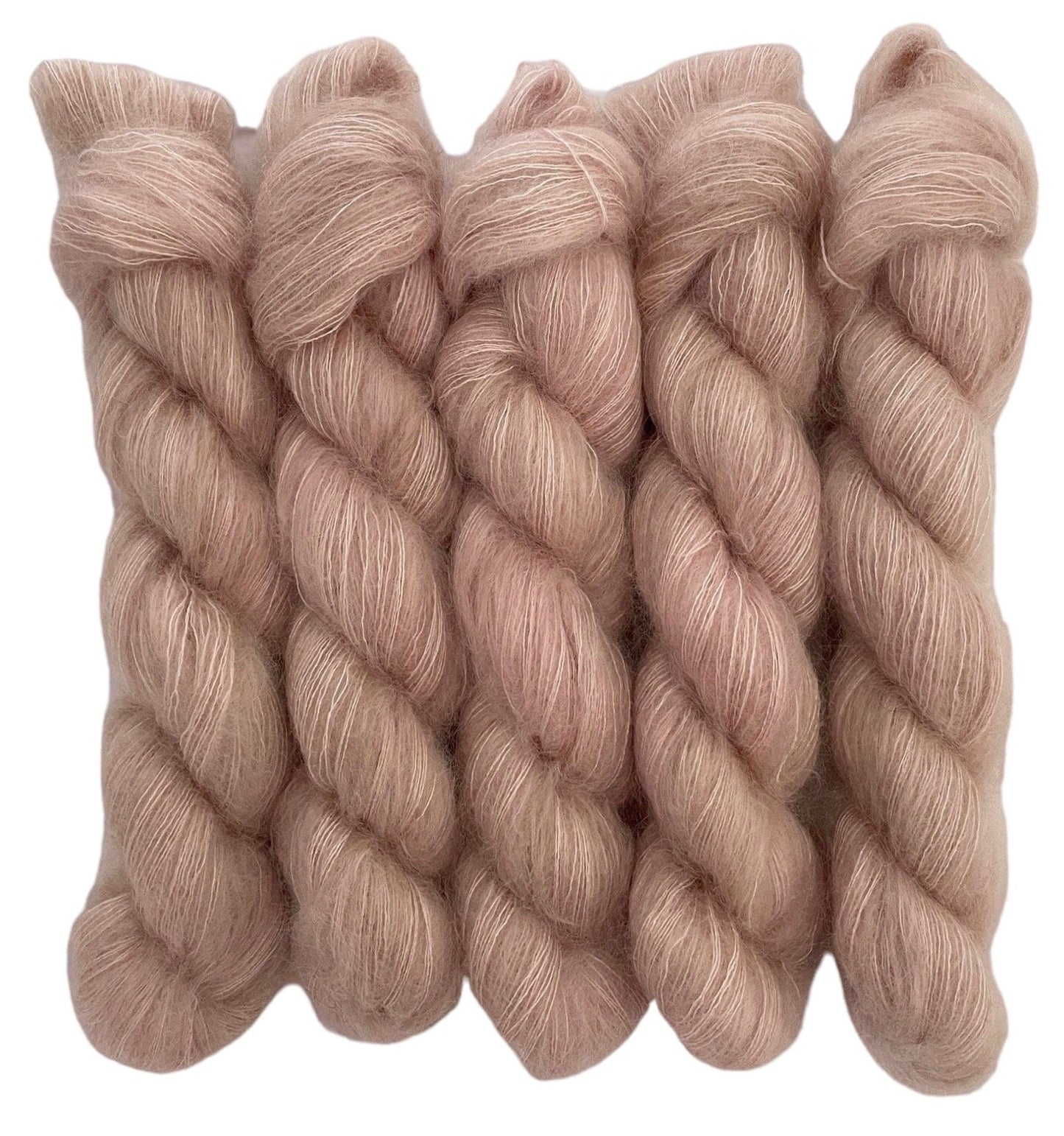 Four beige hand dyed skeins of lace weight mohair and silk yarn on a white background.