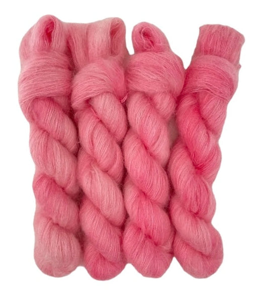 Four pale red hand dyed skeins of lace weight mohair and silk yarn on a white background.
