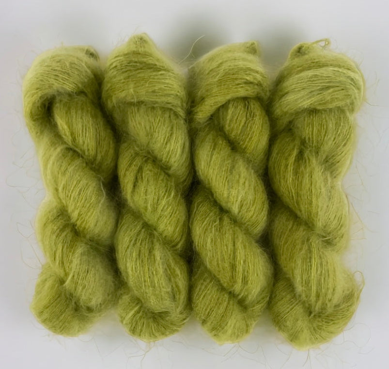 Four green hand dyed skeins of lace weight mohair and silk yarn on a white background.