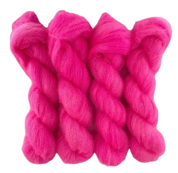 Four bright pink hand dyed skeins of lace weight mohair and silk yarn on a white background.
