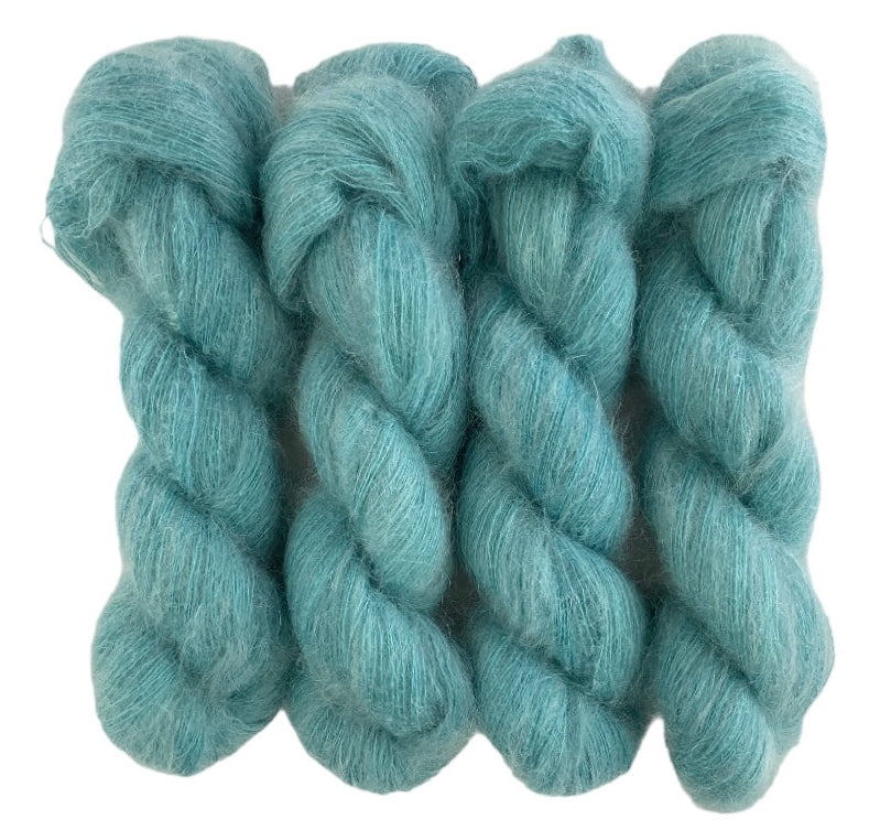 Four green hand dyed skeins of lace weight mohair and silk yarn on a white background.