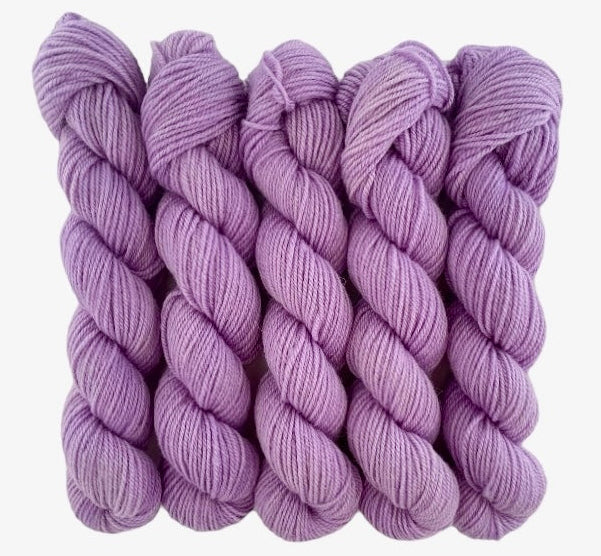 Five skeins of purple merino and blue faced Leicester non-superwash yarn on a white background. Hand dyed. DK