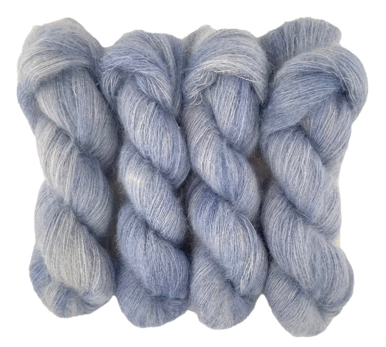 Four pale grey blue hand dyed skeins of lace weight mohair and silk yarn on a white background.