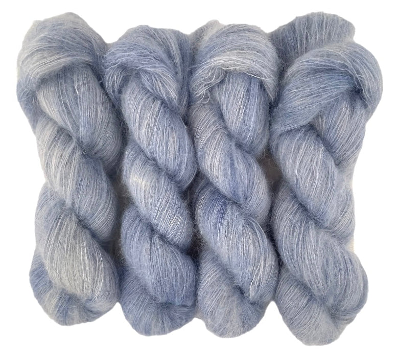 Four pale grey blue hand dyed skeins of lace weight mohair and silk yarn on a white background.