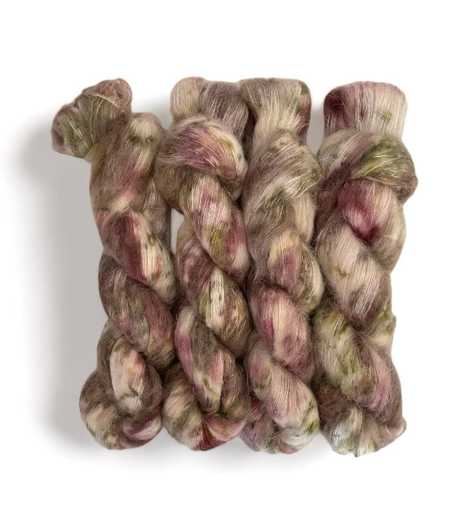 A skein of hand-dyed yarn with a cream base and speckles of green, brown, and mauve.