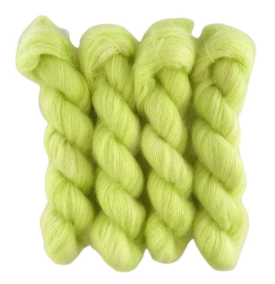 Four bright green hand dyed skeins of lace weight mohair and silk yarn on a white background.