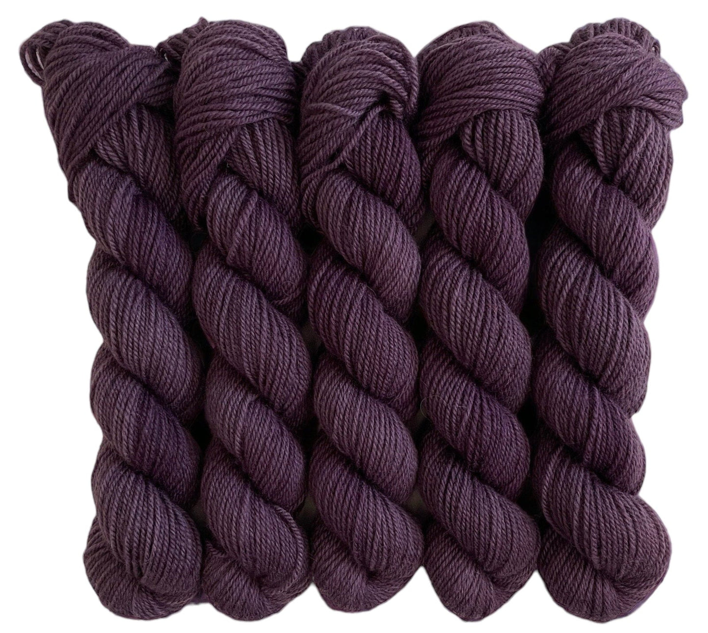 Five skeins of purple merino and blue faced Leicester non-superwash yarn on a white background. Hand dyed. DK
