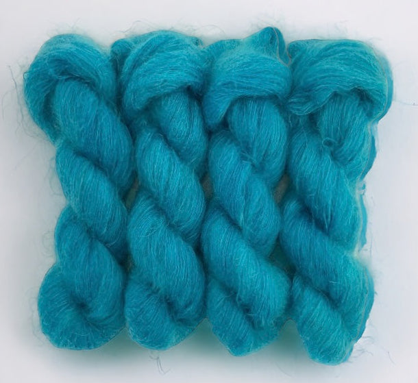 Four blue hand dyed skeins of lace weight mohair and silk yarn on a white background.