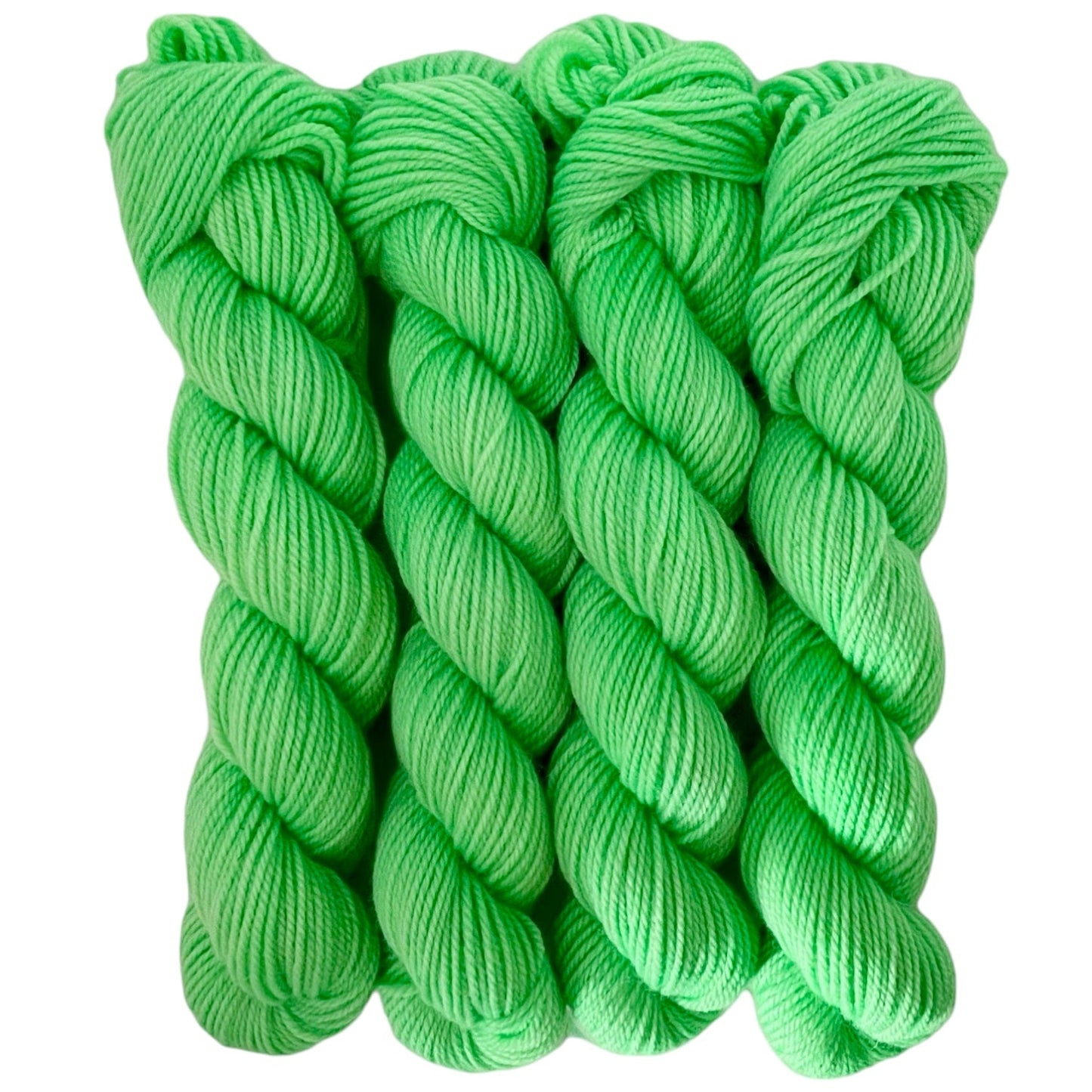 Three skeins of bright green merino and blue faced Leicester non-superwash yarn on a white background. Hand dyed. DK
