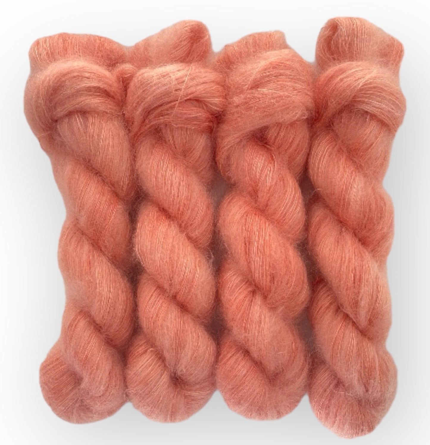 Four pale red hand dyed skeins of lace weight mohair and silk yarn on a white background.