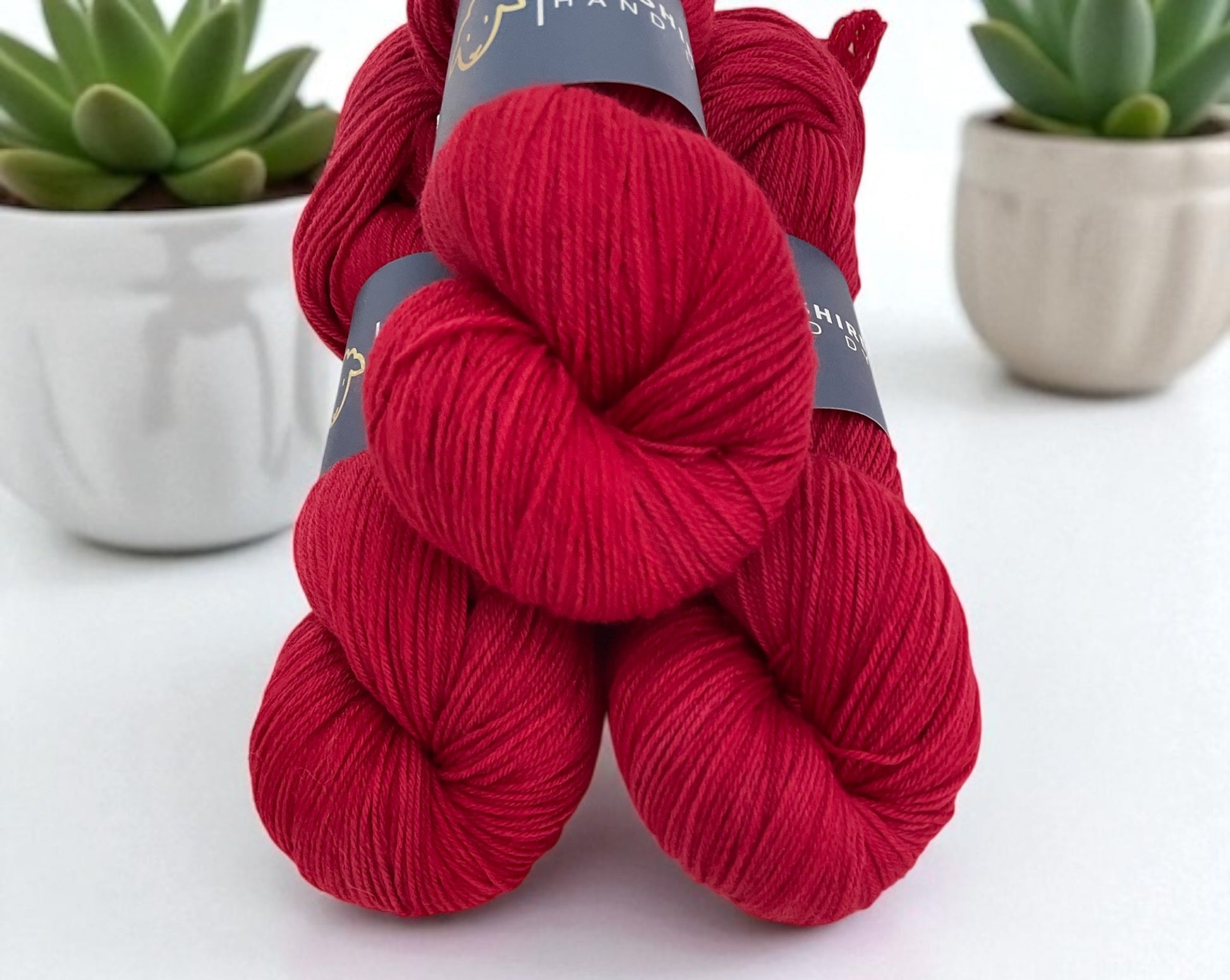 Three skeins of non superwash fingering weight sustainable merino wool, hand dyed red.