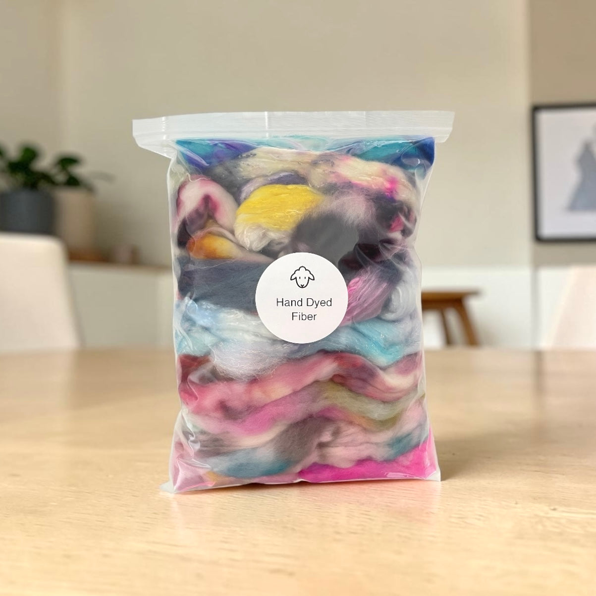 Bag of hand dyed fiber on a wooden table with a neutral background