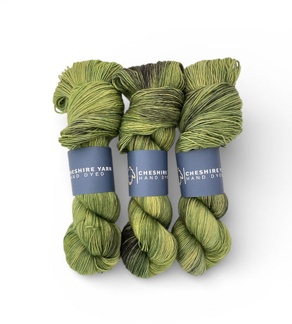 Three skeins of green yarn with blue labels on a white background