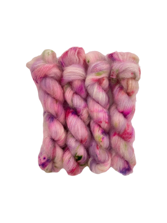 Experience the luxury of FAIRY DUST - a hand dyed yarn crafted with 72% Kid Mohair and 28% Silk. The delicate pink yarn is accented with shades of purple and green, perfect for creating intricate lace designs. Each 50g skein is a dream to work with, giving your projects a touch of elegance.