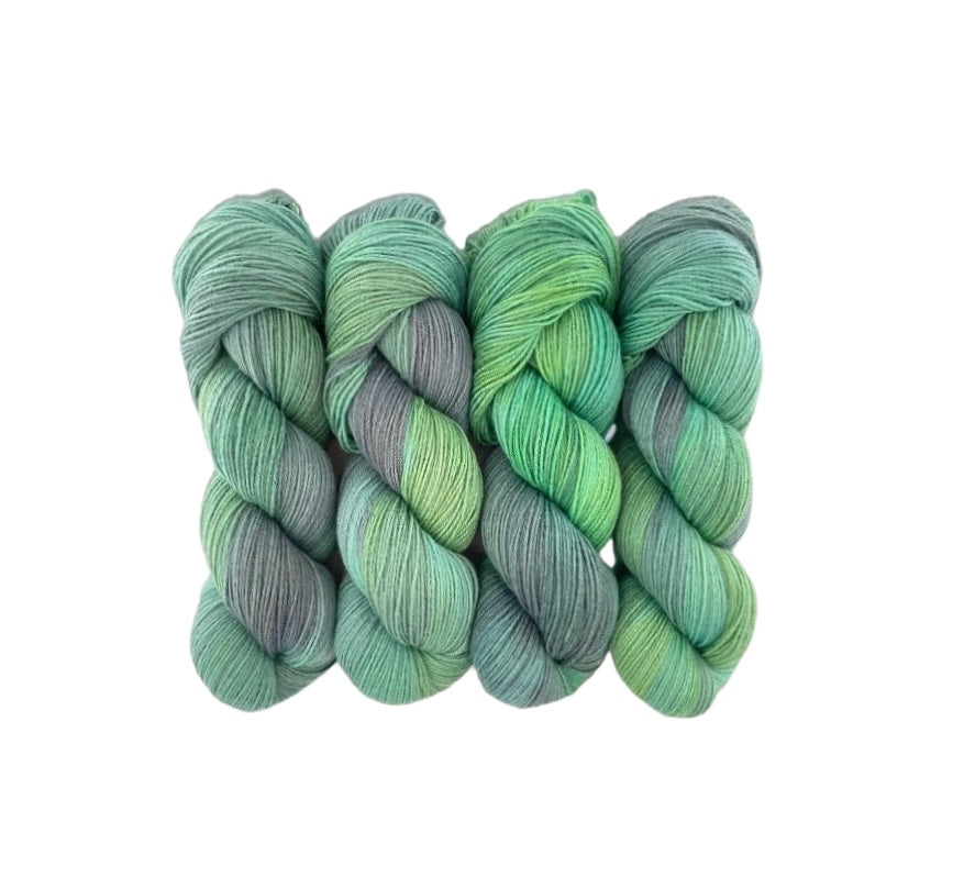 The LATEST LOOK Hand Dyed Yarn is made from 100% sustainable Merino wool and is available in a 100g skein. This fingering/sock weight yarn features a unique blend of  green, and grey tones, making it a versatile and eco-friendly choice for all your knitting and crochet projects.