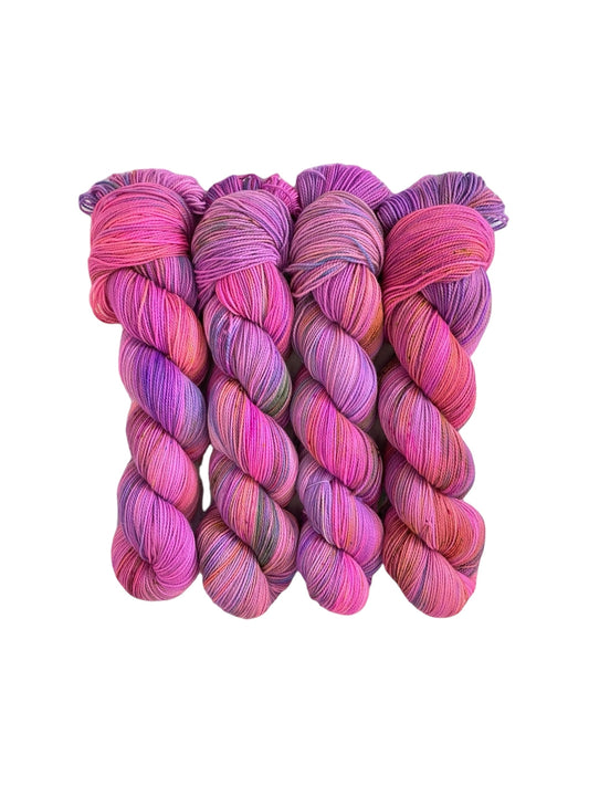 Hand dyed, this fingering/sock weight yarn is made from a luxurious blend of merino wool and nylon. With shades of pink, orange, and purple, each 100g skein is uniquely vibrant and soft to the touch. Perfect for creating long-lasting, colorful projects.