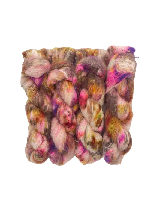 Indulge in luxury with COCOA DRIZZLE, a hand-dyed yarn made from baby suri alpaca and mulberry silk. Perfect for knitting and weaving, this lace weight yarn boasts a cream-colored base with pops of brown, pink, and green. Elevate your projects with this high-quality, mixed color skein.